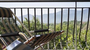 Una cadira amb dibuixos ratllats i estructura metàl·lica, col·locada en un balcó amb barana metàl·lica.