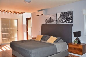 A bedroom with a bed, a nightstand, a lamp, and a cityscape artwork on the wall. - Casa Valentin Gama Casas Freda (San Luis Potosi)