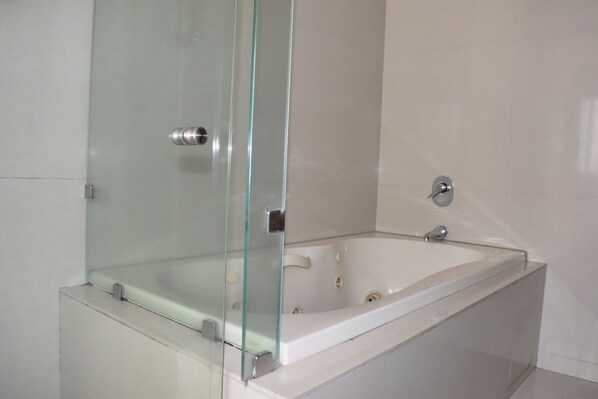 A modern bathroom with a glass-enclosed shower, a white bathtub, and a chrome faucet. - Casa Valentin Gama Casas Freda (San Luis Potosi)
