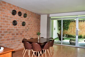 A dining area with a brick wall, a wooden table, and chairs. - Casa Valentin Gama Casas Freda (San Luis Potosi)