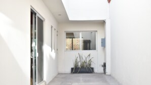 A narrow, white-walled corridor with a door and a window.
