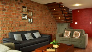 A living room with a brick wall, two sofas, a coffee table, and a staircase.