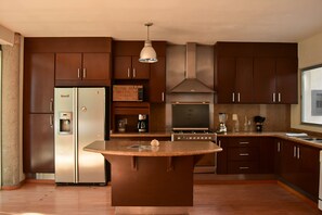 A modern kitchen with dark wooden cabinets, stainless steel appliances, and a central island. - Casa Valentin Gama Casas Freda (San Luis Potosi)