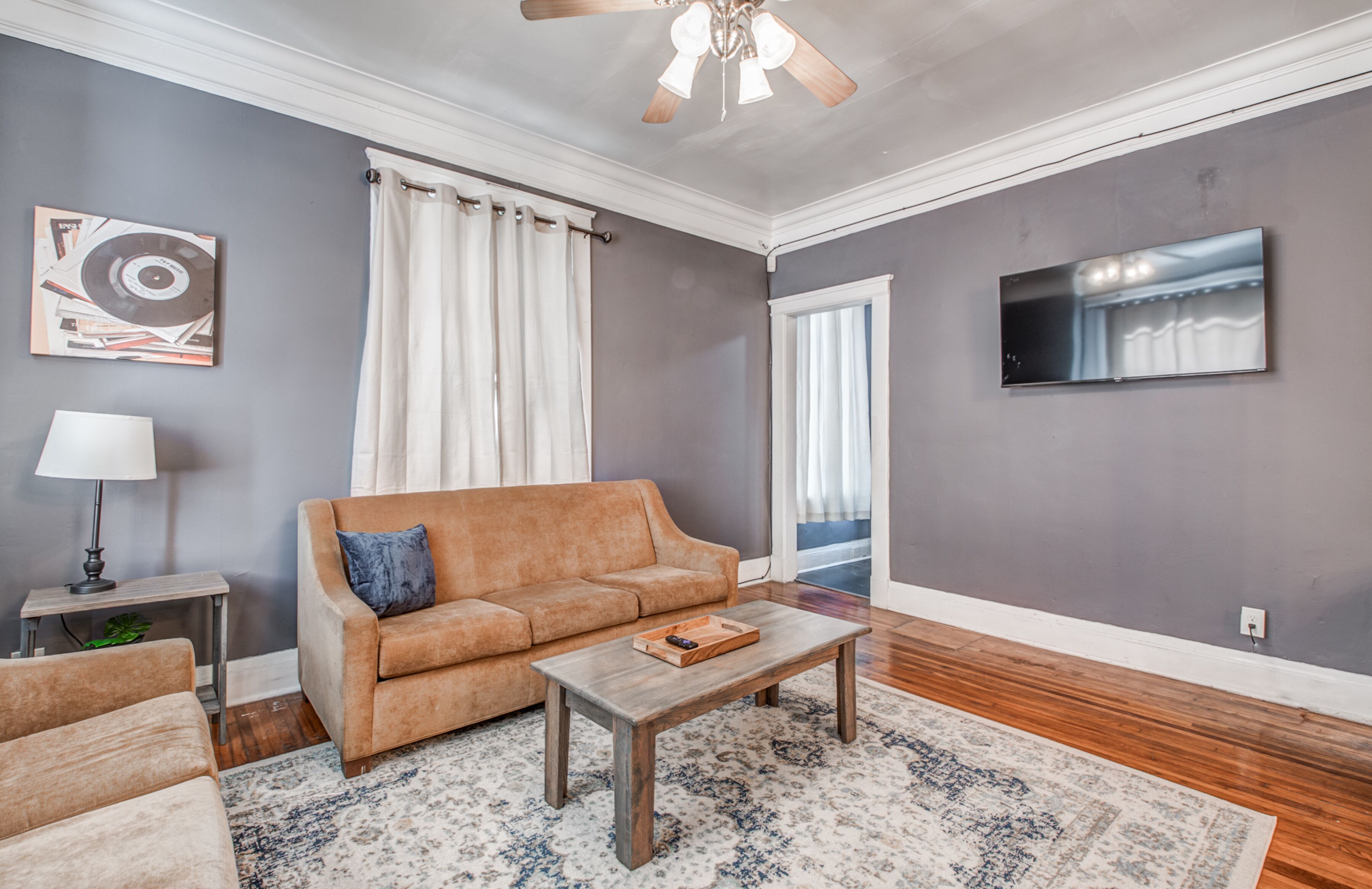A living room with a sofa, coffee table, and a TV mounted on the wall.
