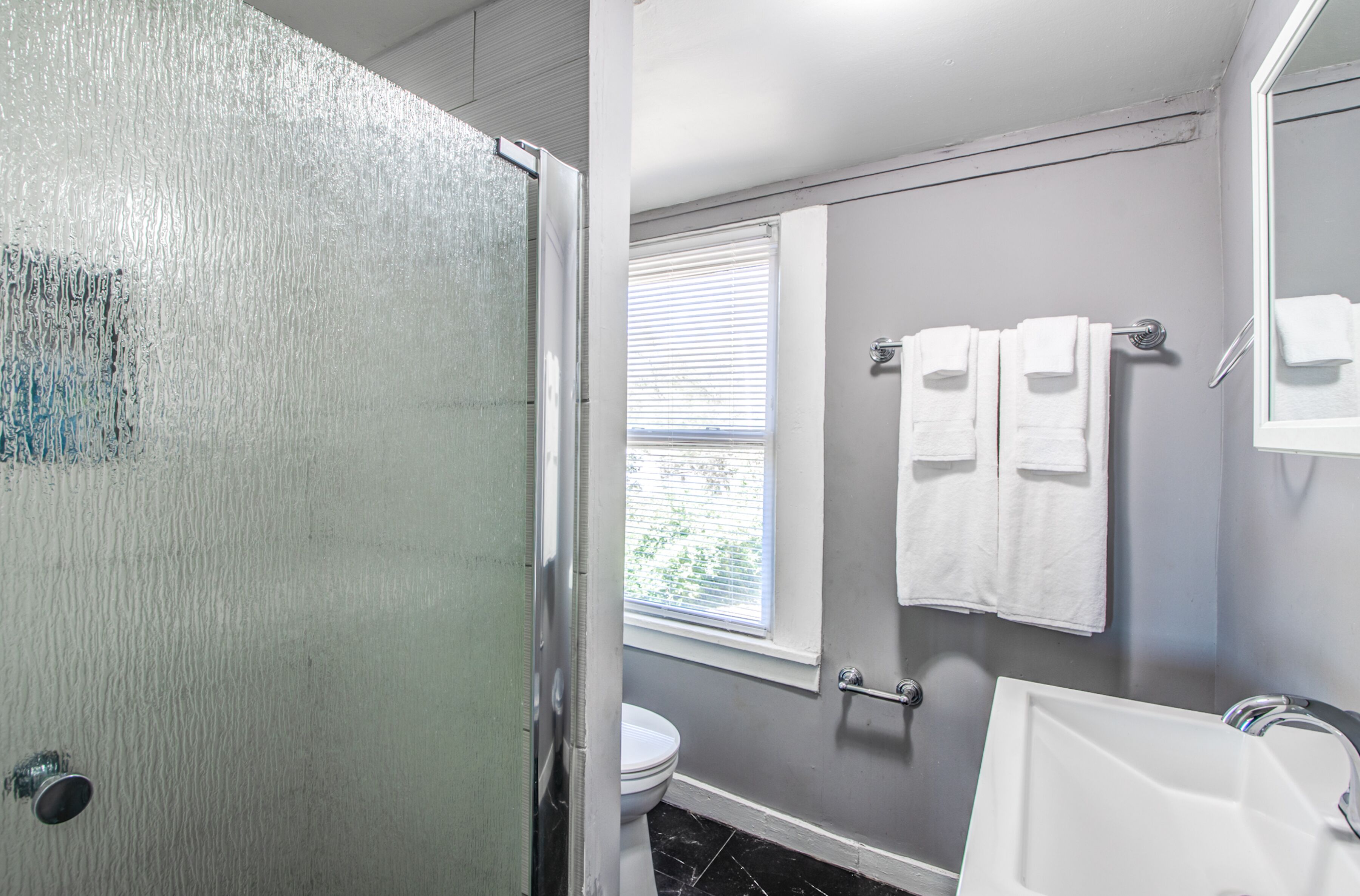 A bathroom with a shower, toilet, and sink.