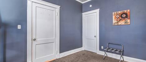 A room with two white doors, a grey carpet, and a metal bench.