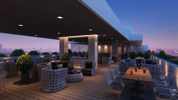 A rooftop terrace with seating areas, planters, and a city view.