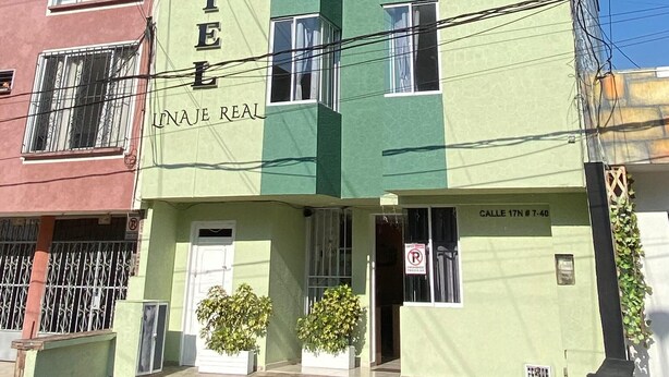 A hotel building with a green facade and multiple windows.