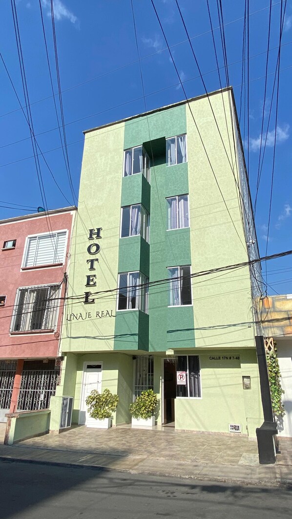 A hotel building with a green facade and multiple windows.