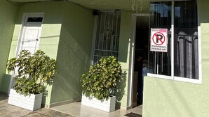 A hotel building with a green facade, a sign reading "HOTEL NAJE REAL", and a "No Parking" sign.