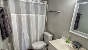 A bathroom with a toilet, sink, and shower curtain. - Havens by the Sea STE A Cozy 2BR Beachside Escape (North Myrtle Beach)
