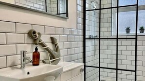 A modern bathroom with a white sink, a toilet, and a glass shower enclosure. - Minerva Close by Tŷ SA (Newport)