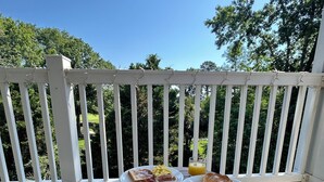 A breakfast table with plates of food and drinks on a balcony with a white railing and greenery in the background. - Bright 2 BR, Fully Equipt, 3rd Floor Cozy Condo in Myrtle Beach (Myrtle Beach)