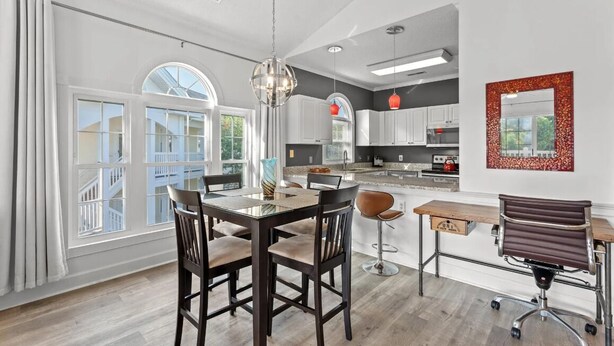 A spacious kitchen with modern appliances, a dining area with a glass table, and a large window offering a view of the outside. - Bright 2 BR, Fully Equipt, 3rd Floor Cozy Condo in Myrtle Beach (Myrtle Beach)