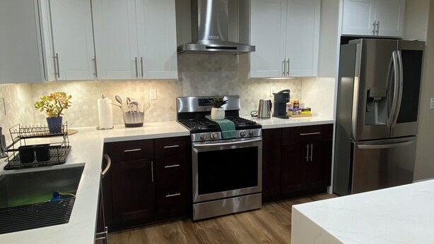 Una cocina moderna con armarios blancos, electrodomésticos de acero inoxidable y piso de madera.