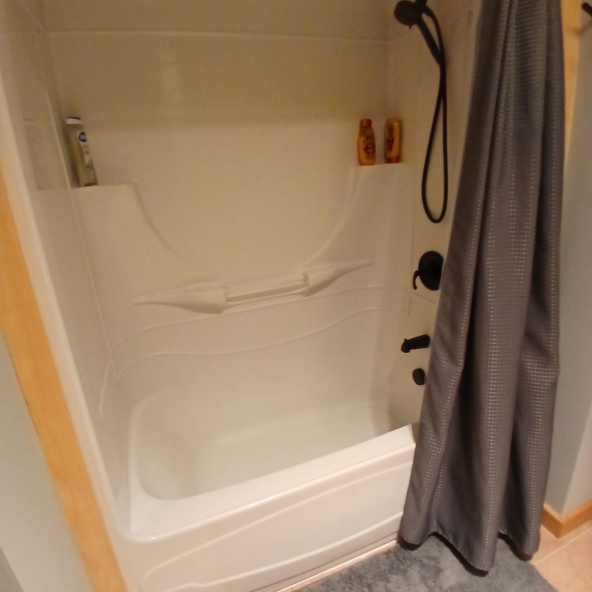Un bagno con una vasca, una tenda da doccia e due flaconi di shampoo appesi al muro.