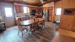 A spacious kitchen with wooden cabinets, a dining table with chairs, and a ceiling fan.