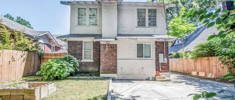 A two-story house with a front yard, a wooden fence, and a brick exterior.