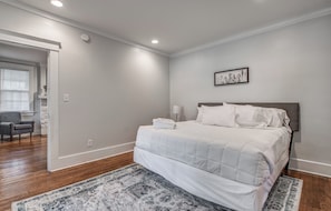 A bedroom with a bed, a nightstand, a chair, a window, and a door. - The Rolling Stone Near Downtown (Memphis)