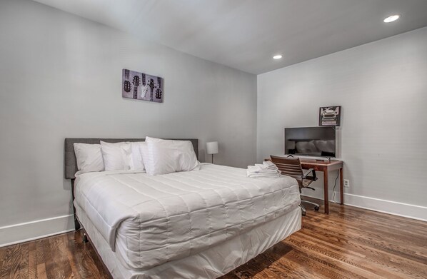 A hotel room with a large bed, a desk, a chair, and a television. - The Rolling Stone Near Downtown (Memphis)
