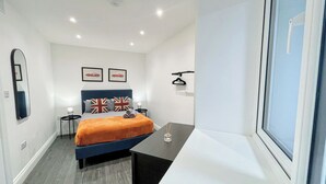 Une chambre à coucher moderne avec un lit, des tables de chevet, un miroir et une fenêtre.