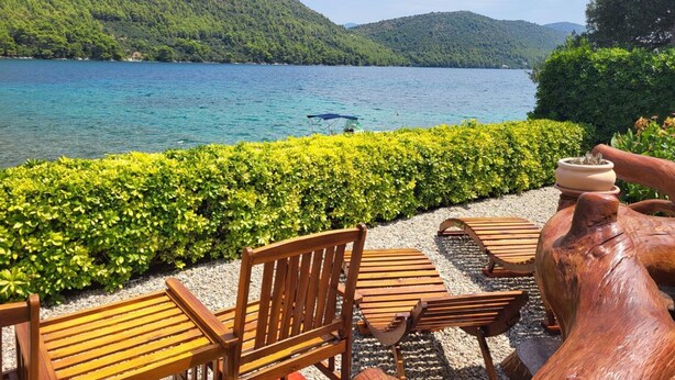 Un espace de détente aménagé au bord du lac, avec des bancs et des chaises en bois, entouré de verdure et offrant une vue sur le lac et les bateaux.