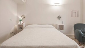 Ein Schlafzimmer mit einem großen Bett, einem Nachttisch mit Lampe, einem Sessel und Dekoration an den Wänden.
