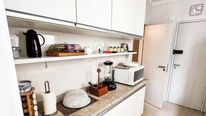 Une cuisine moderne avec des armoires blanches, un four à micro-ondes et divers appareils de cuisine disposés sur le plan de travail.