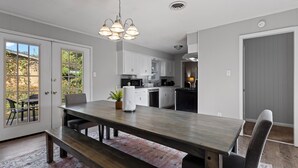 Una cocina moderna con armarios blancos, una mesa de comedor con bancos y una lámpara colgante.