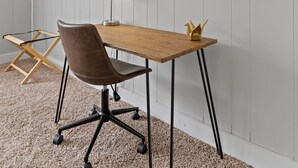 Una habitación con un escritorio de madera, una silla de oficina marrón, un espejo redondo y una lámpara.