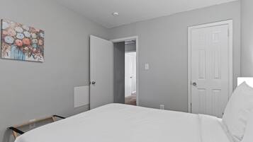 A bedroom with a bed, a door, a closet, and a painting on the wall.