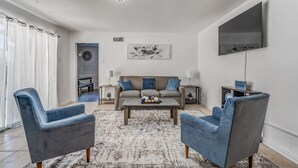 A modern living room with a sofa, two armchairs, a coffee table, and a flat-screen TV. - Near Parks Tranquil Fox Trails (Memphis)