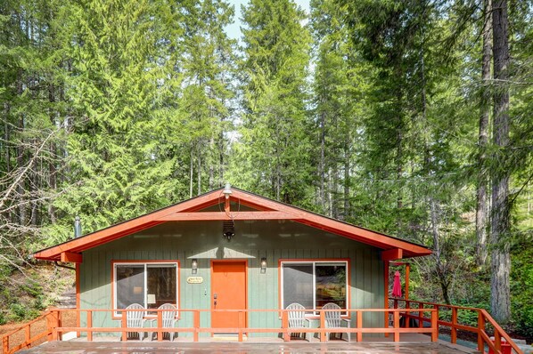 Eine Holzhütte mit rotem Dach, einer Veranda mit Stühlen und einem Schild mit der Aufschrift 'Alpine Lodge'.