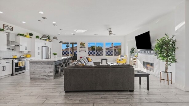 A modern kitchen with white cabinets, a central island, and a dining area with chairs.