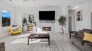 A modern living room with a fireplace, a sofa, a coffee table, and a yellow armchair.