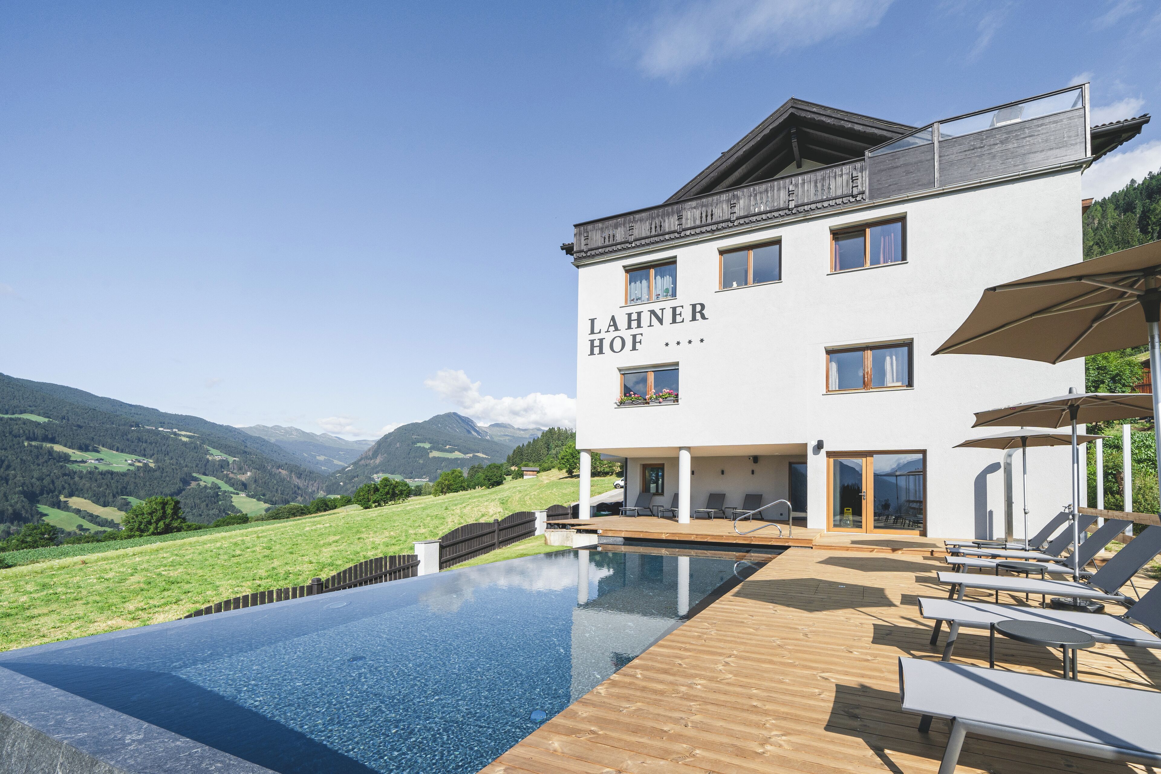 Un hôtel moderne doté d’une piscine, de chaises longues et offrant une vue sur les montagnes.