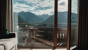 A room with a large sliding glass door leading to a balcony with a mountain view. - Hotel Lahnerhof (Vipiteno)