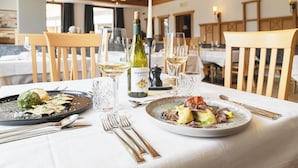A dining table set with plates of food, wine glasses, and cutlery. - Hotel Lahnerhof (Vipiteno)
