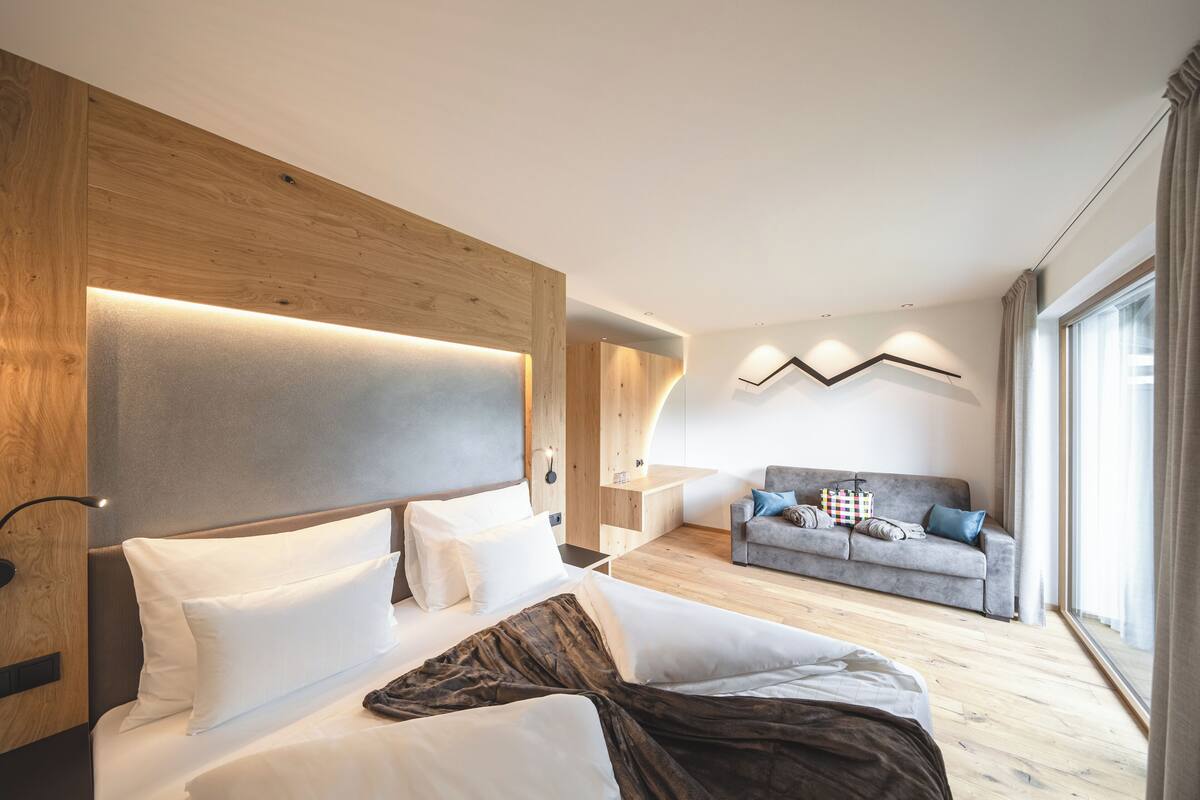Quarto de hotel moderno com uma cama grande, um sofá e uma escrivaninha.