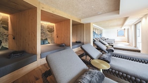 A spa area with wooden walls, multiple massage chairs, and a large window providing natural light. - Hotel Lahnerhof (Vipiteno)