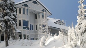 Ein großes, mehrstöckiges Haus mit schneebedecktem Dach und umliegenden Bäumen.