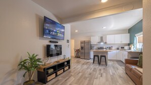 A modern living room with a flat-screen TV, a potted plant, and a wooden entertainment unit. - Downtown Garden Escape (Casper)