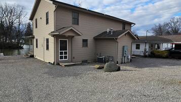 A two-story house with a front porch, a small attached garage, and a gravel driveway.
