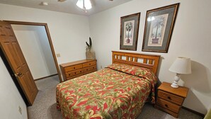 Una camera da letto con un letto, un comodino, una cassettiera e due quadri appesi al muro.