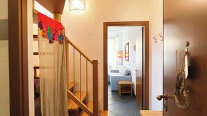 A staircase with a wooden handrail leading to a room with a blue sofa and a small table. - Casa Marta - Affitti Brevi Italia (Lecco)