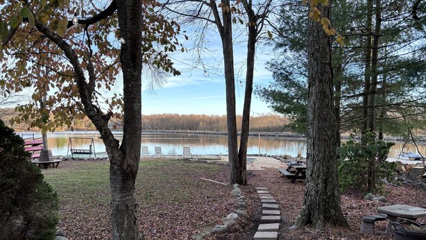 A wooded area with a clear path leading to a lake, picnic tables, and benches. - 5-Bedroom Lakefront, private beach wifi AC boat & kayaks near ski, casino (Tobyhanna)