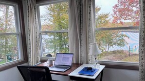 A workspace with a laptop, a mug, and a lamp on a desk by a window with curtains. - 5-Bedroom Lakefront, private beach wifi AC boat & kayaks near ski, casino (Tobyhanna)