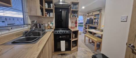Una cocina compacta con armarios de madera, una estufa y un lavabo.