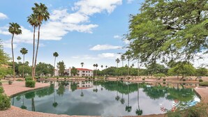 A serene outdoor pool area with palm trees, a reflection pool, and a building in the background. - Fully Furnished Remodeled Condo 2 Bed 2 Bath Superstition Springs on 1 level  (Mesa)