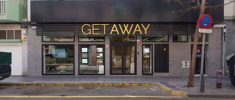 En modern byggnad med en skylt som visar ordet ”GETAWAY”, med en entré av glas och ett träd framför.